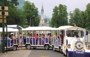 Petit train touristique de Lourdes devant l'entrée du sanctuaire